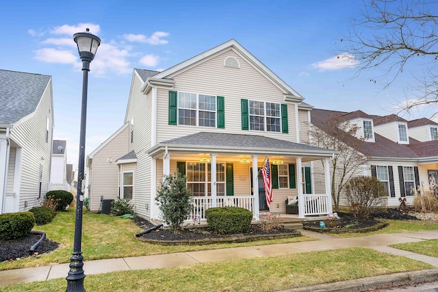 traditional home with a porch, cooling unit, and a front lawn