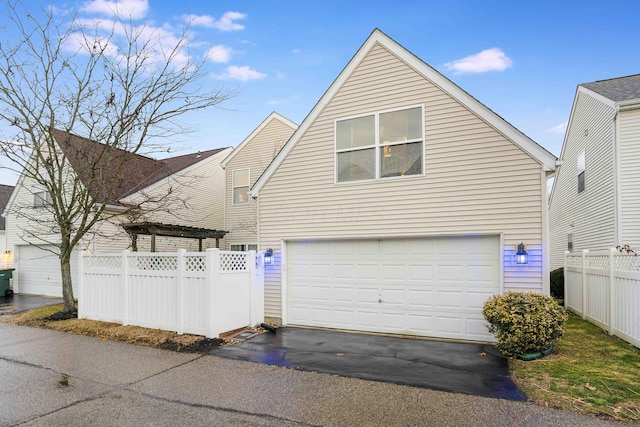 exterior space featuring an attached garage, fence, and aphalt driveway