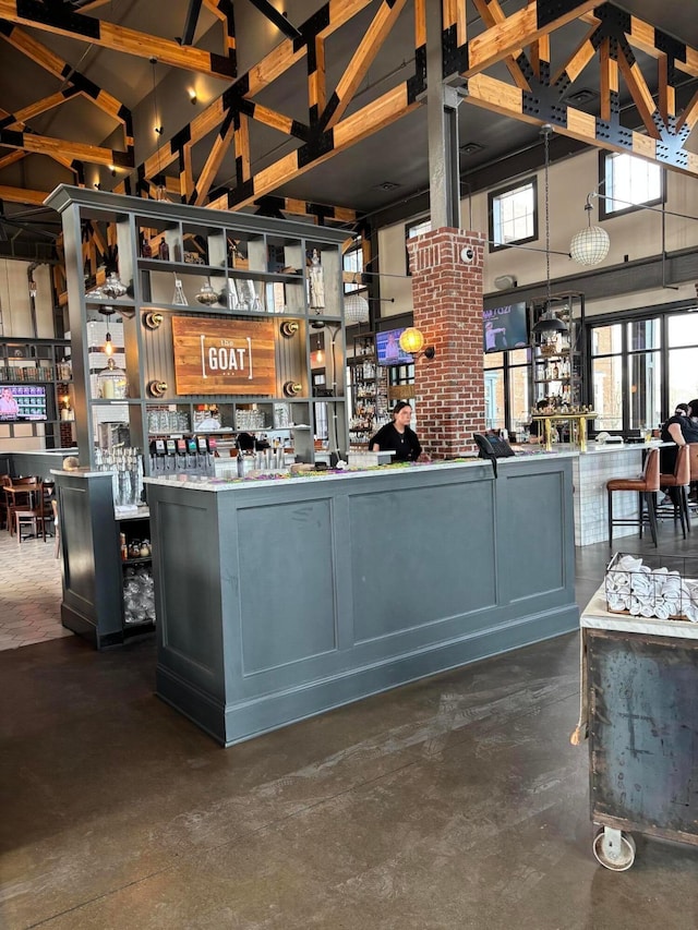 interior space featuring concrete flooring, a dry bar, and a towering ceiling