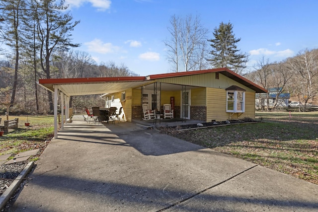 view of front of property with a porch, an attached carport, concrete driveway, and brick siding