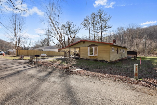 view of front of home featuring aphalt driveway, a chimney, and fence