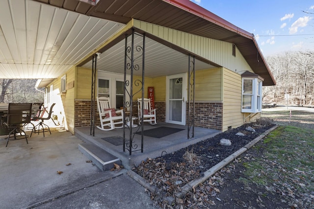 exterior space with covered porch and brick siding