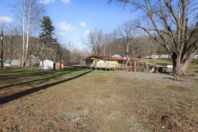 view of yard with a storage shed, a deck, and an outbuilding