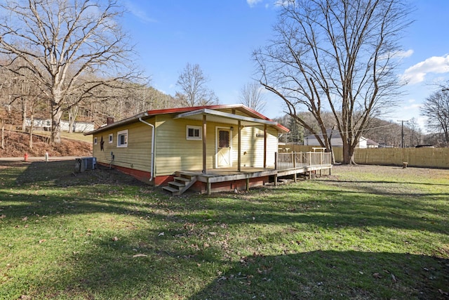 back of property featuring fence, central AC unit, a wooden deck, and a lawn