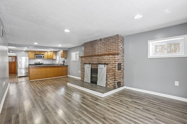 unfurnished living room with dark wood-style flooring, plenty of natural light, and a brick fireplace