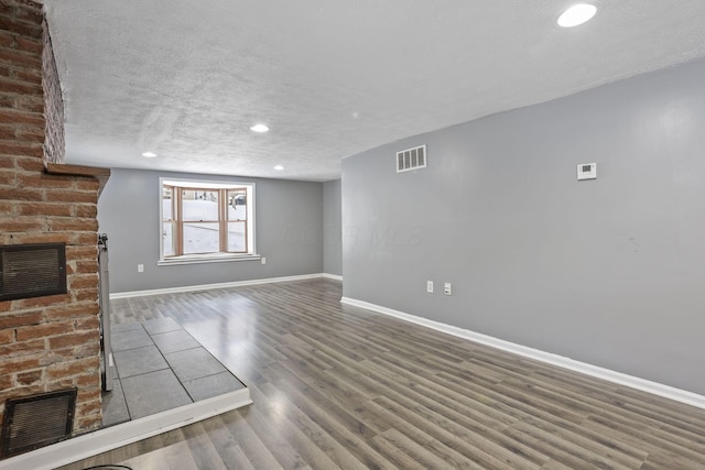 unfurnished living room featuring a fireplace, wood finished floors, visible vents, and baseboards