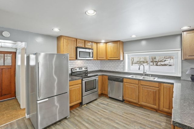 kitchen with stainless steel appliances, dark countertops, a sink, and a wealth of natural light