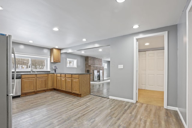 kitchen with a peninsula, light wood-style floors, baseboards, and stainless steel appliances