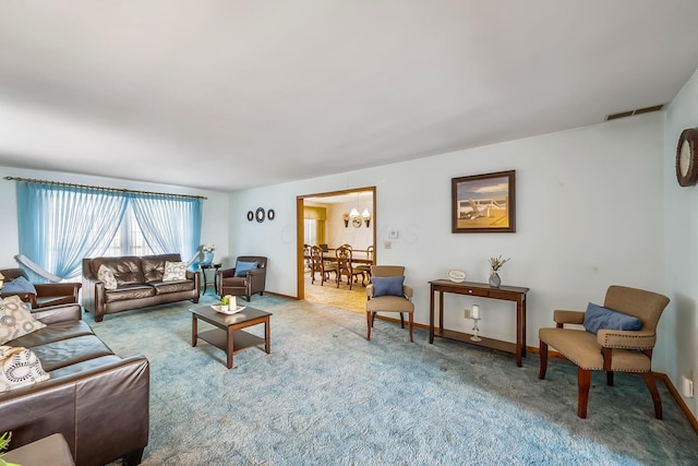 living area with baseboards, a notable chandelier, visible vents, and light colored carpet