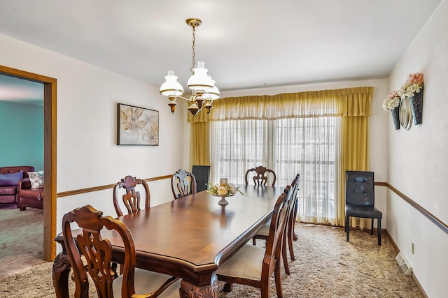 carpeted dining area featuring a chandelier and baseboards