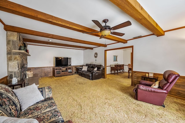 carpeted living area with wooden walls, visible vents, a wainscoted wall, ceiling fan, and beam ceiling