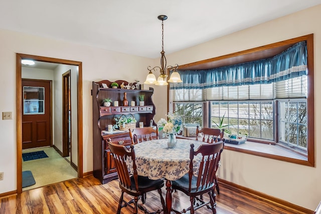 dining room with a notable chandelier, baseboards, and wood finished floors