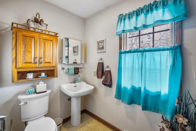 half bathroom featuring a sink, toilet, and baseboards