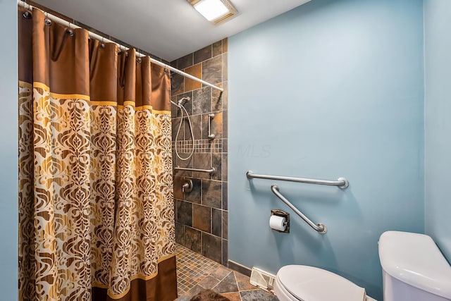 bathroom featuring baseboards, tiled shower, visible vents, and toilet