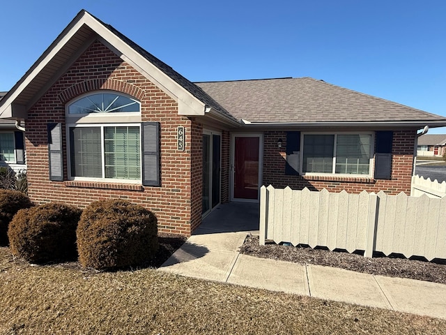 single story home with brick siding, roof with shingles, and fence