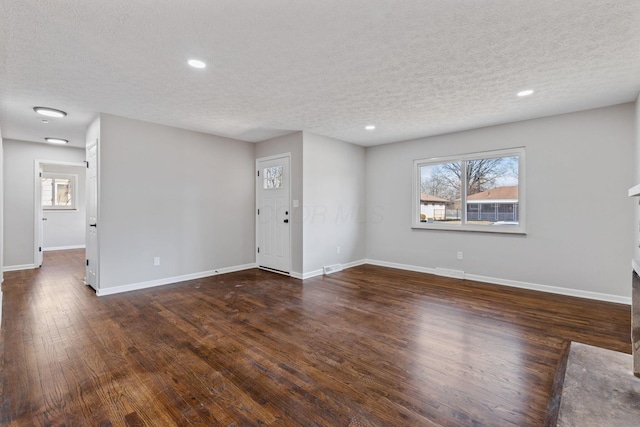 unfurnished living room with a textured ceiling, recessed lighting, visible vents, baseboards, and dark wood finished floors