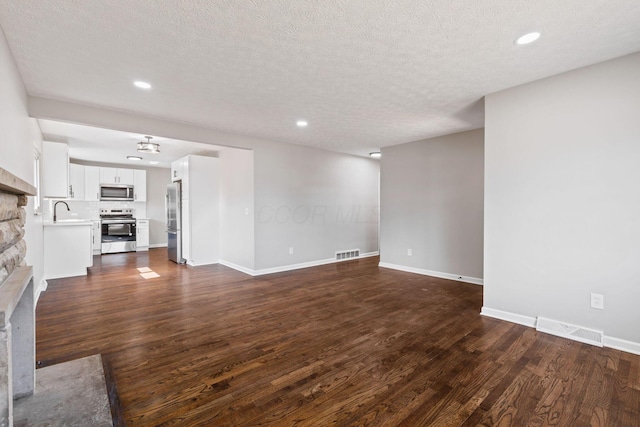 unfurnished living room with dark wood-style floors, visible vents, and baseboards