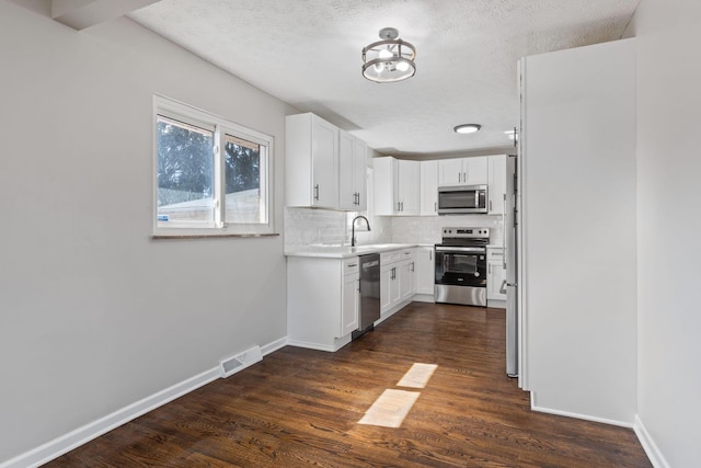 kitchen with visible vents, white cabinets, light countertops, appliances with stainless steel finishes, and tasteful backsplash