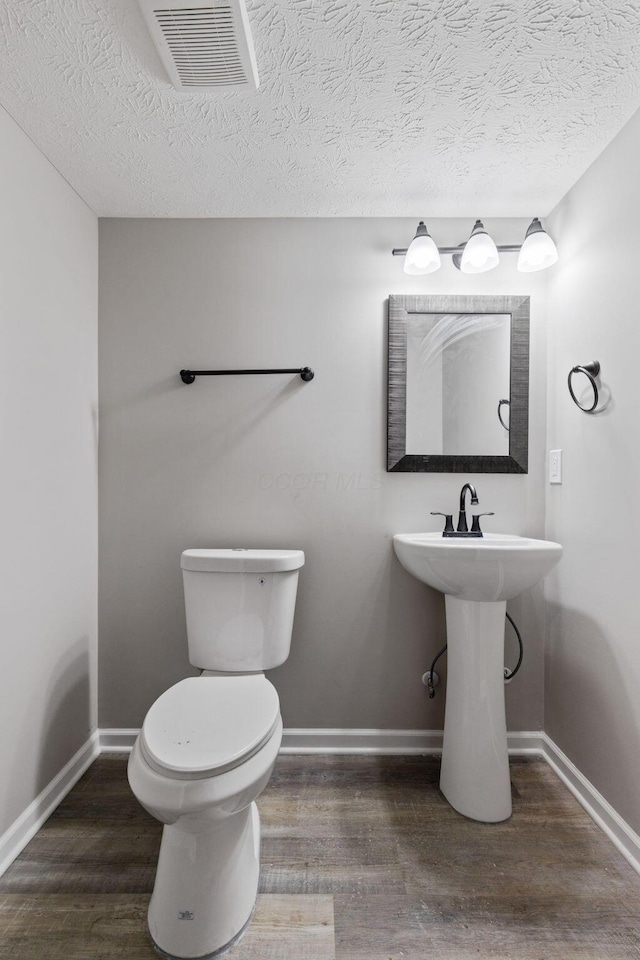 bathroom with wood finished floors, visible vents, and baseboards