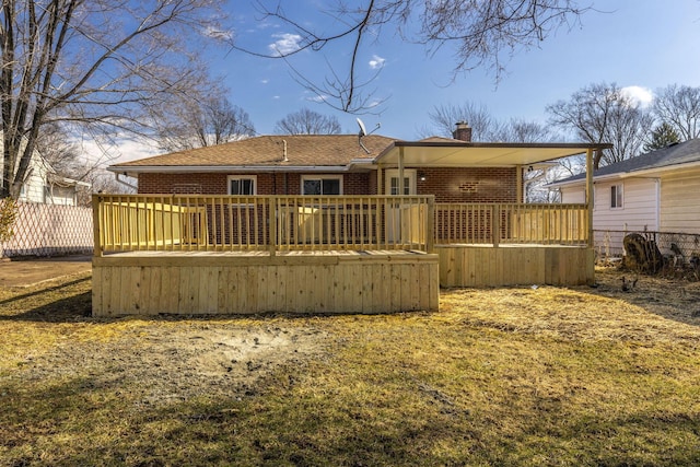 back of property with a chimney, brick siding, fence, and a deck