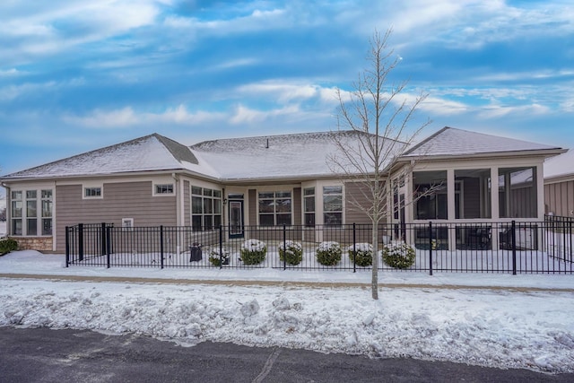 snow covered house with a sunroom and fence