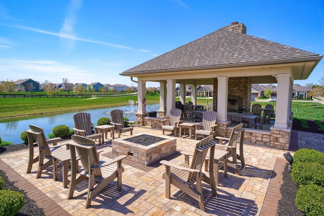 view of patio featuring a gazebo, an outdoor fire pit, an outdoor stone fireplace, and a water view