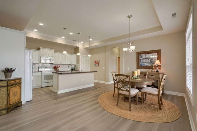 dining space with light wood-style floors, baseboards, visible vents, and arched walkways