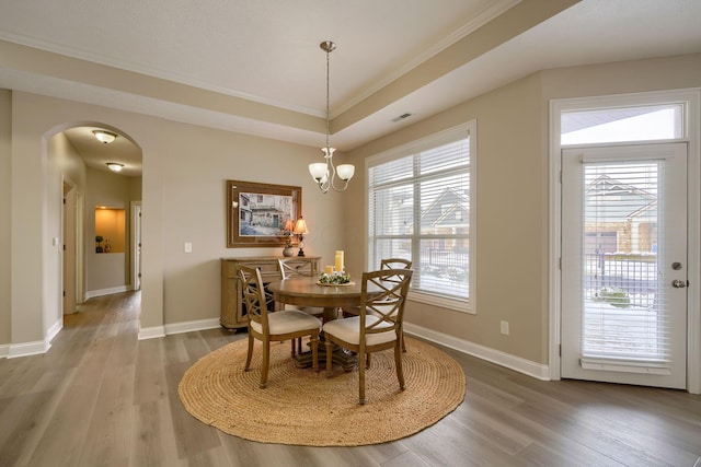 dining area featuring arched walkways, baseboards, and wood finished floors