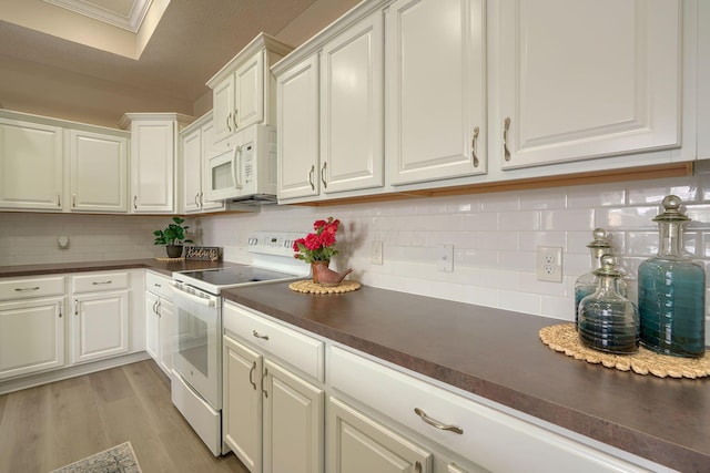 kitchen featuring dark countertops, white appliances, white cabinetry, and light wood-style flooring