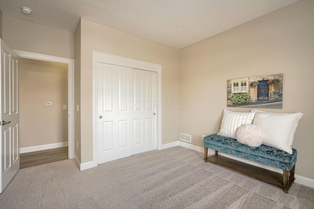 sitting room with carpet floors, visible vents, and baseboards