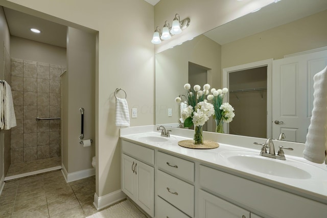 bathroom with double vanity, tile patterned flooring, a walk in shower, and a sink