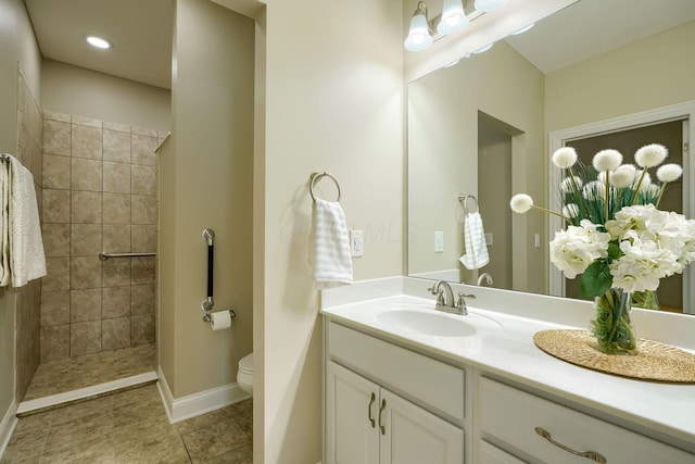 bathroom featuring baseboards, toilet, tile patterned flooring, a tile shower, and vanity