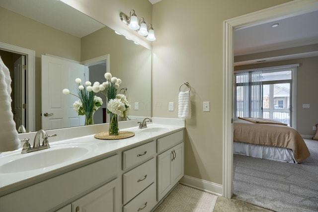 bathroom with ensuite bathroom, double vanity, a sink, and baseboards