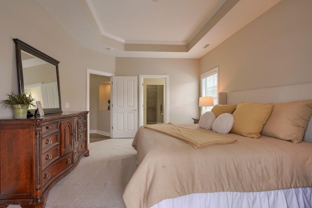 bedroom with a tray ceiling, ornamental molding, light carpet, ensuite bath, and baseboards