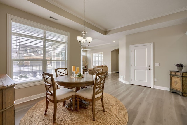 dining area featuring baseboards, visible vents, arched walkways, ornamental molding, and wood finished floors