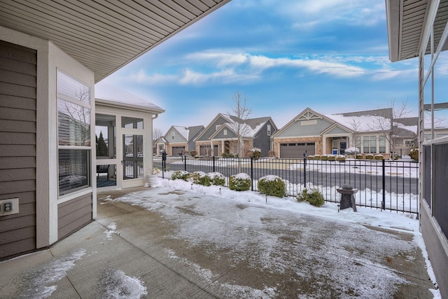 snow covered patio with a residential view and fence