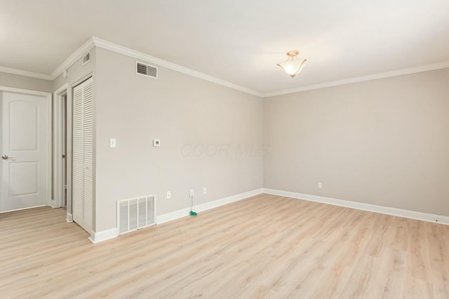 empty room featuring visible vents, light wood finished floors, and ornamental molding