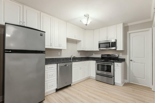 kitchen with crown molding, light wood-type flooring, appliances with stainless steel finishes, white cabinetry, and a sink