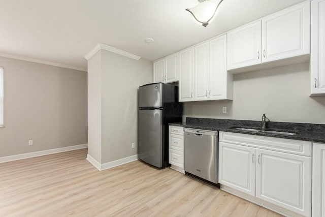 kitchen with baseboards, ornamental molding, a sink, appliances with stainless steel finishes, and white cabinetry