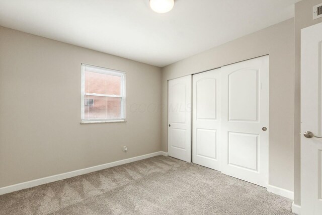 unfurnished bedroom with a closet, baseboards, visible vents, and carpet flooring