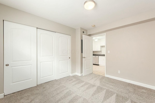 unfurnished bedroom featuring baseboards, visible vents, a closet, and light carpet