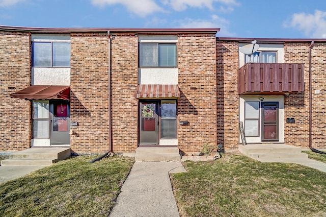 view of property with brick siding and a front lawn