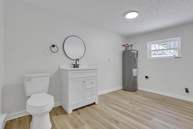 half bathroom with a baseboard radiator, toilet, wood finished floors, vanity, and water heater