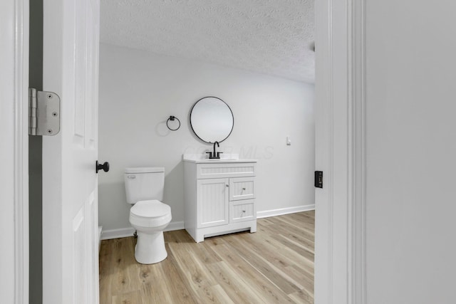 bathroom featuring baseboards, a textured ceiling, toilet, and wood finished floors