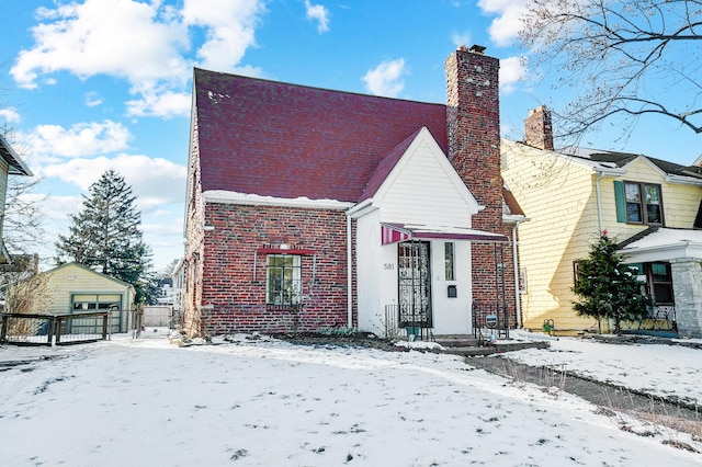 view of front of house with a garage, brick siding, and a chimney