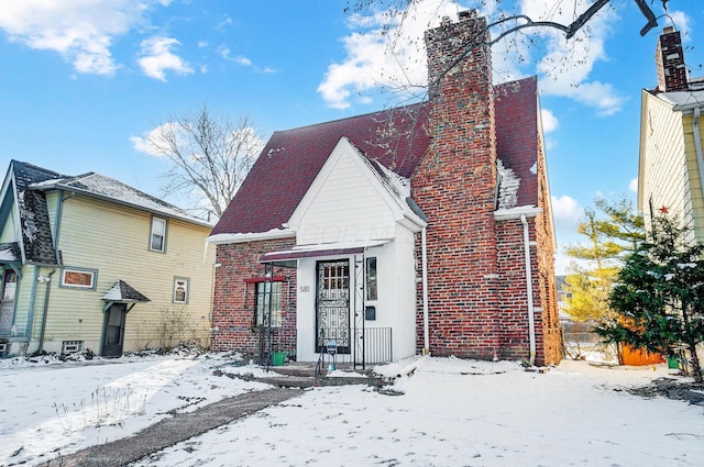 view of front of property with a chimney and brick siding