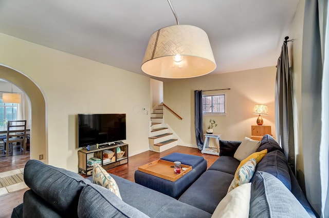 living area with stairs, arched walkways, and wood finished floors