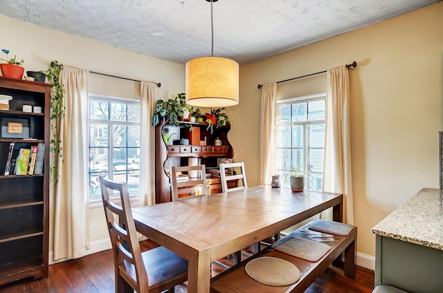 dining area with a textured ceiling, dark wood-style flooring, and baseboards