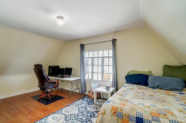 bedroom with baseboards, vaulted ceiling, and wood finished floors