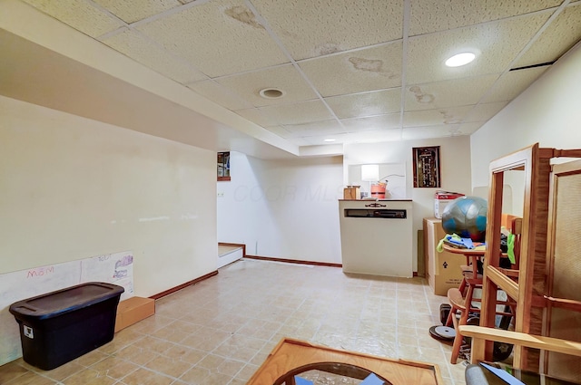 interior space featuring a paneled ceiling and baseboards